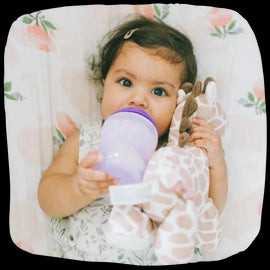 Bebeluș fericit ținând un biberoan fără BPA pentru o alimentație sigură.